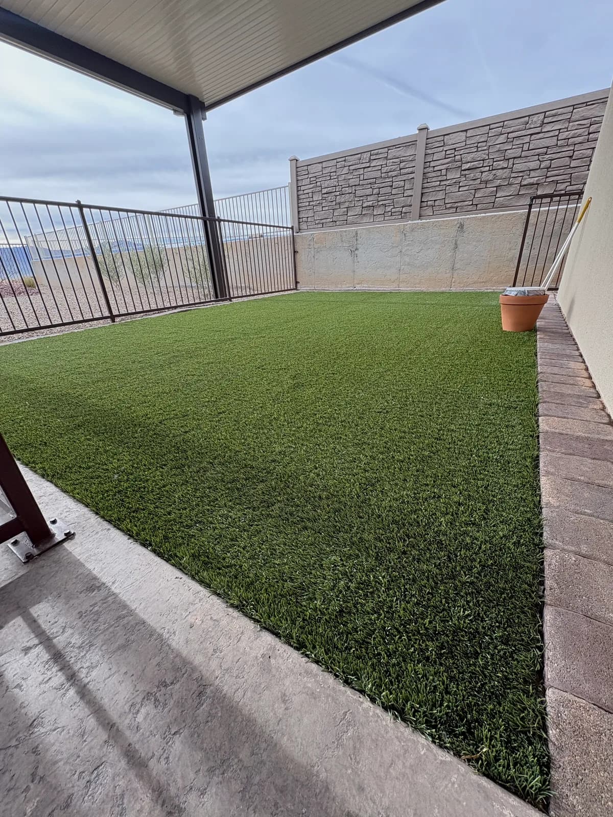Fenced backyard artificial turf area cleaned and treated for pet odor, ready for daily use
