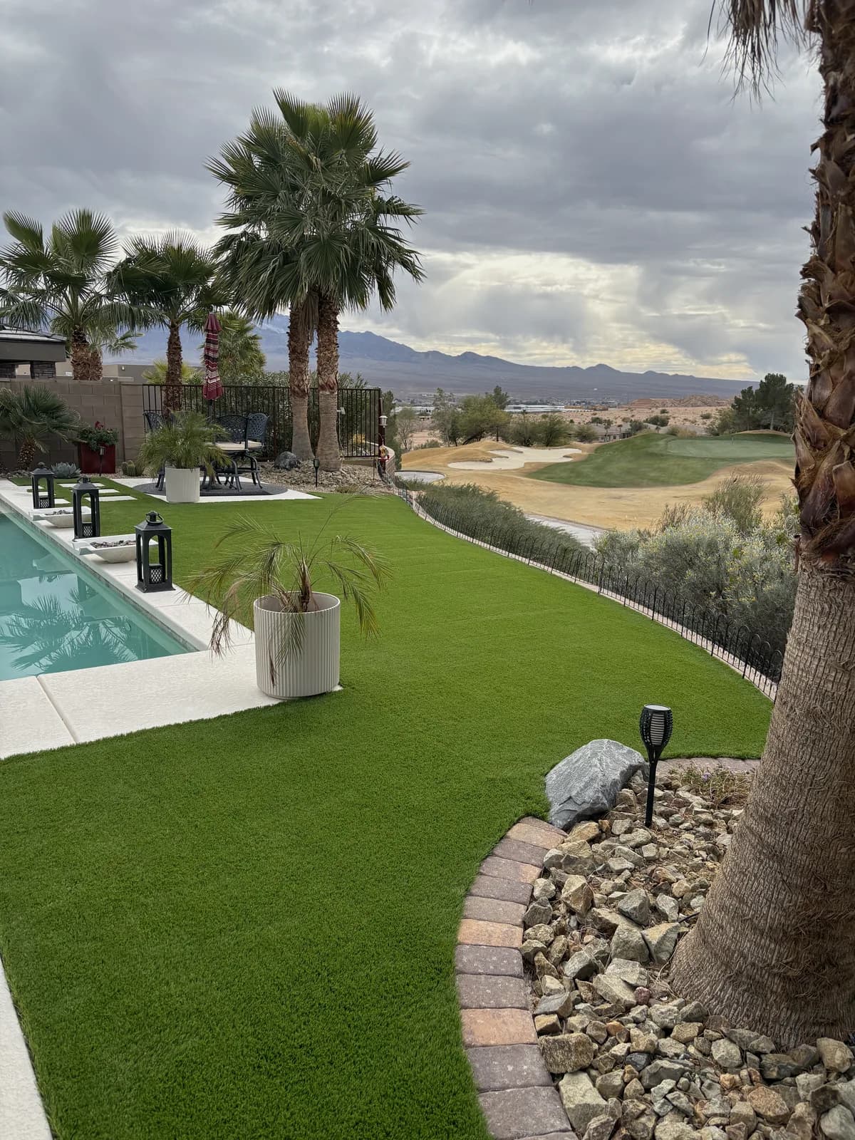 Restored artificial turf pool deck lawn with palm trees and mountain view after a power brooming pass